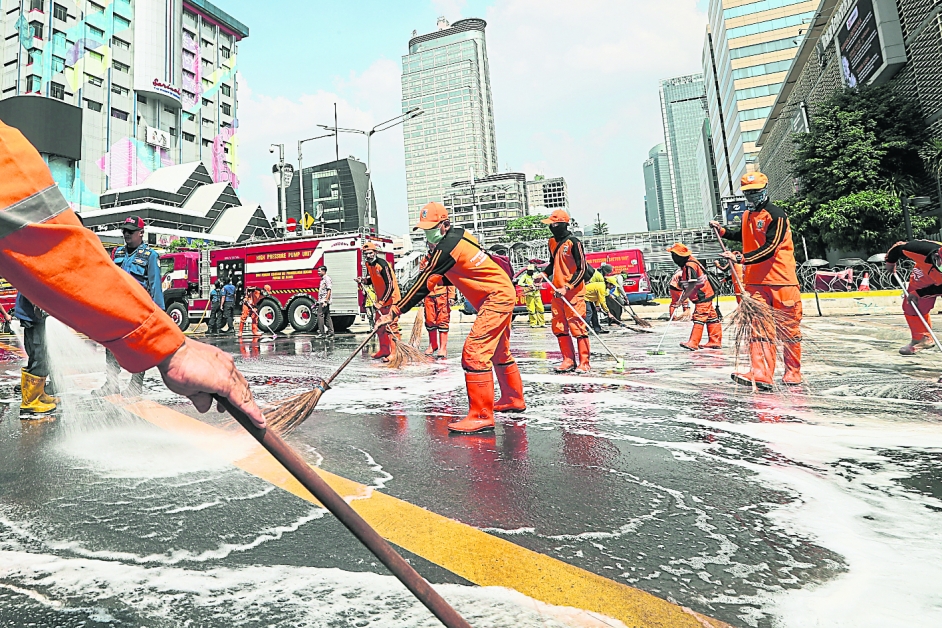 印尼消防员和清洁工周四在选举监督委员会大楼外进行清理工作。（欧新社）