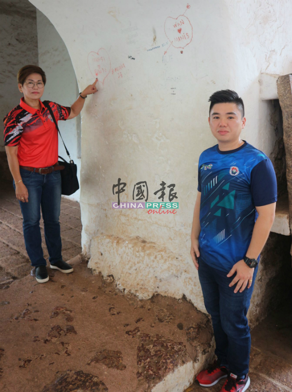 傅秋霞（左）指教堂内的墙面，遭涂鸦破坏，右为许佳勋。