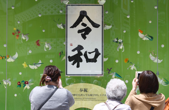日本周三进入“令和”元年，东京一间商场的橱窗展示的“令和”字眼，引起民众拍照留念。（法新社）