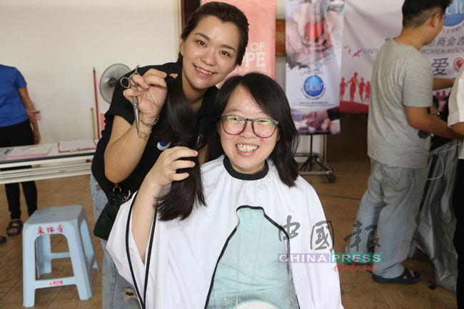 参与慈善义剪的捐赠者，与理发师一起领着头发合影。