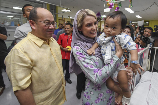 王储妃（左2）在儿童病房逗弄一名小童开心，王储（左）全程与王储妃在一起。