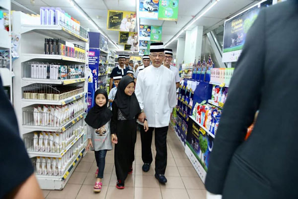 亲民的元首阿都拉（右）牵着小女孩的手，逛超市挑用品。