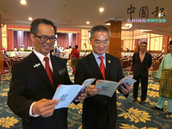 邱培栋国会议员（右起）及刘志良行政议员，翻阅甲州政府执政一周年报告。