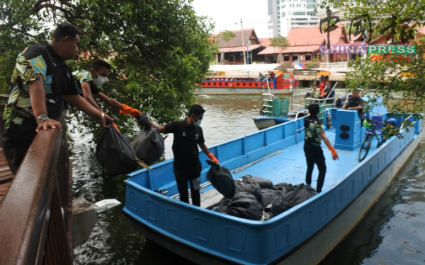 工作人员将一包包的垃圾搬上船。