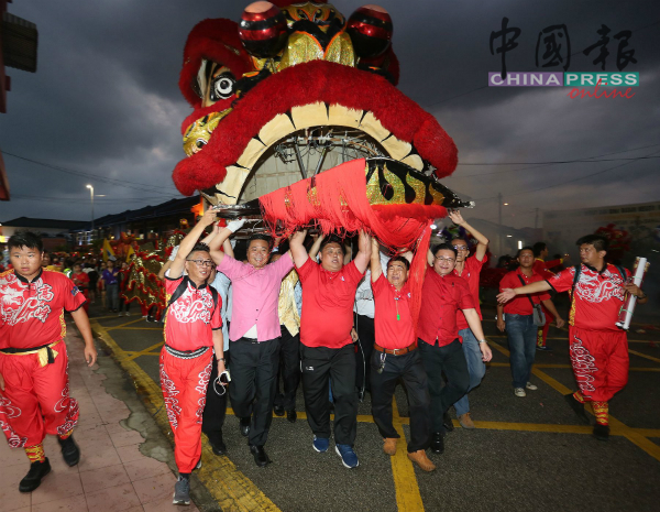 今年的鸡场街闹元宵活动，郑国球（左2）担任马六甲新春年景布置嘉年华会工委会主席时，与大伙一同高举“天下第一狮”。