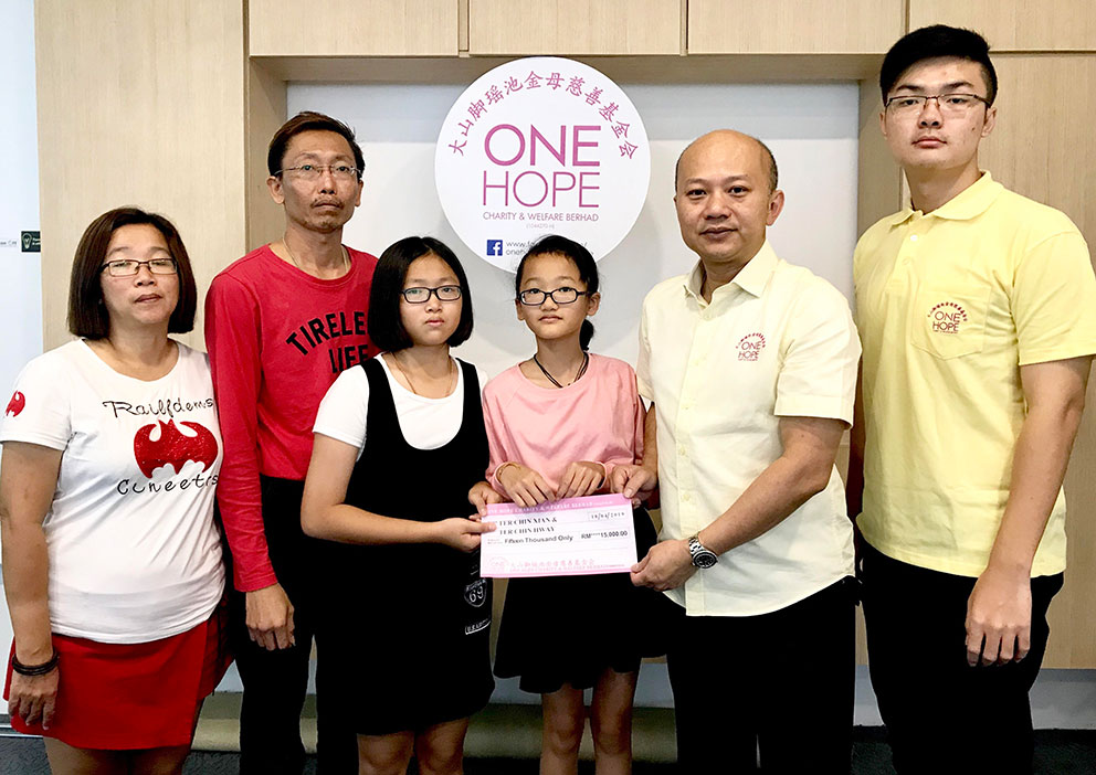 蔡瑞豪（右2）代表基金会移交1万5000令吉，给姐妹花一家，左起为母亲余丽萍、父亲郑春华、晶慧和晶璇。