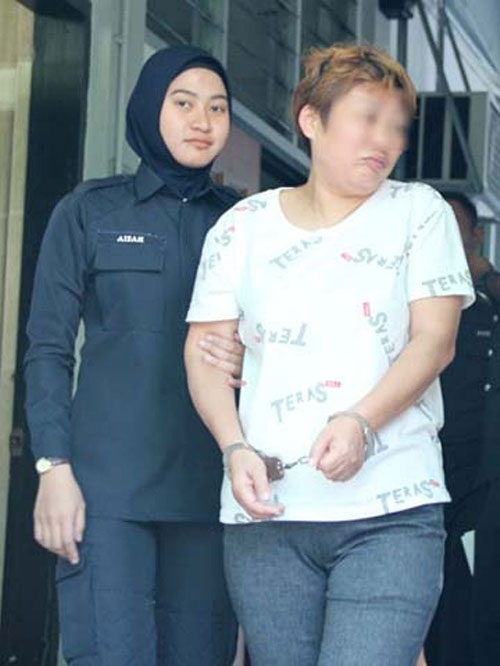 涉祈福党诈骗的中国籍妇女（右）由女警押去警局调查。