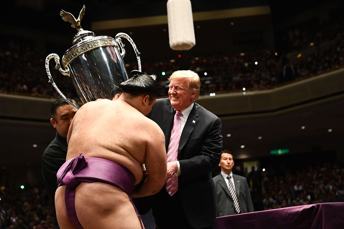 特朗普将“美国总统杯”颁发给相扑赛夺冠力士，奖杯上还有一个象征美国的白头海雕雕像，特朗普笑得见牙不见眼。