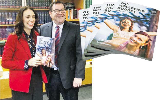 纽西兰总理阿德恩（左）拿着介绍《幸福预算案》刊物（右图），与财长罗伯逊合照。