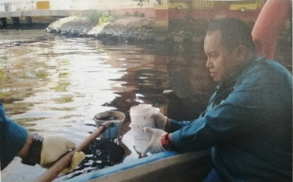 环境局官员到马六甲河索取样本，以送往化验。