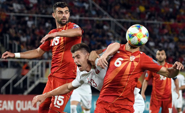 皮亚泰克（中）在北马其顿球员夹击中冲顶。他攻进本仗唯一进球，助波兰在G组保持全胜。（法新社）