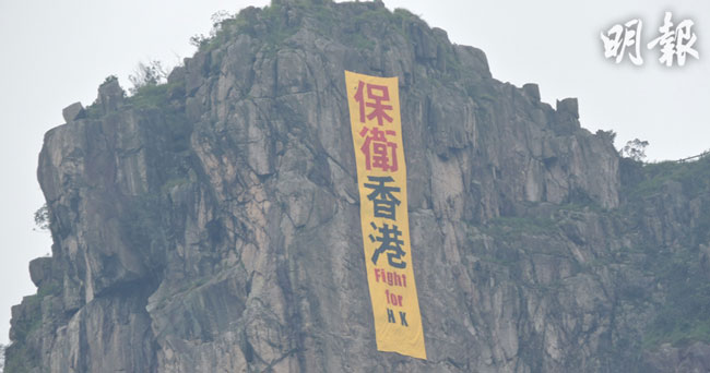 直幡悬挂于狮子山头，写有红黑色的“保卫香港 Fight for HK”字样。