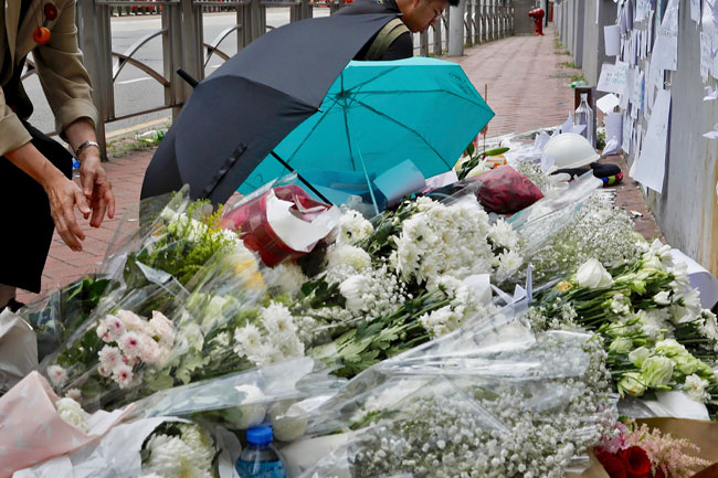 市民到金钟道太古广场堕楼现场，献花和祈祷。（美联社）