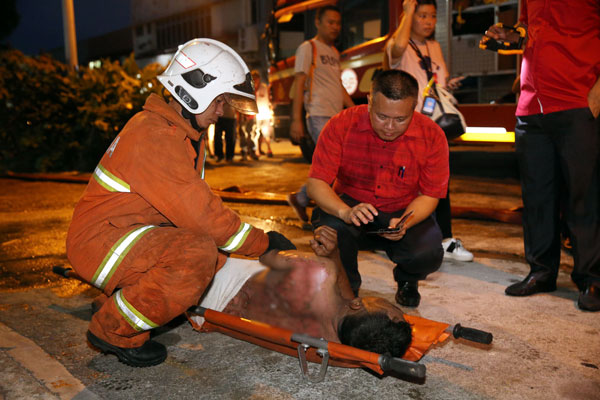 被火灼伤背部的男租客要求吴金财（右）帮忙致电老板告知发生火患及被烧伤。