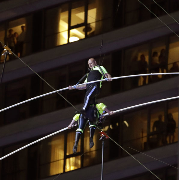 美国知名高空特技团体“飞翔瓦伦达家族”兄妹档，周日在25层楼高的钢索上，穿越美国纽约的知名景点时报广场。（美联社）
