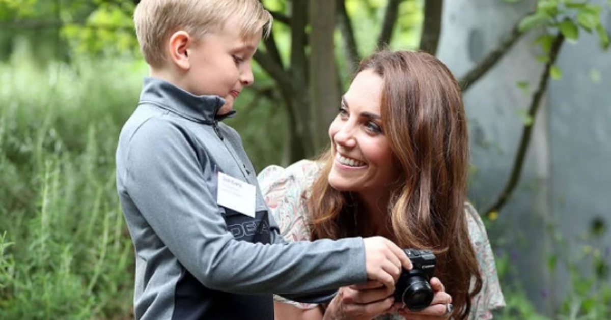 凯特王妃向孩子们介绍有关的摄影元素，如肖像，光线和色彩等。图为凯特王妃与小男孩互动。