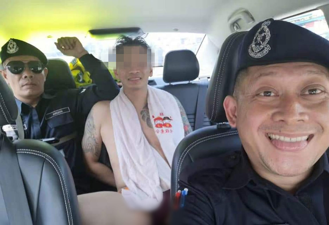 在街上大闹的华裔男子满面笑容被警方扣押上巡逻车。