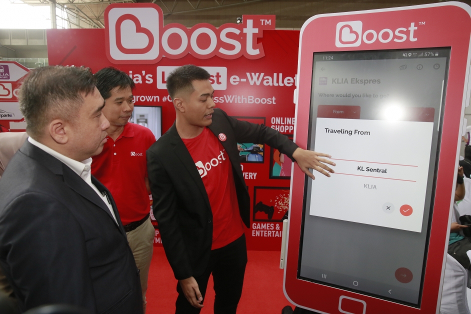 陆兆福（左）正在听取Boost代表讲解该公司的无现金服务系统。
