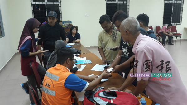 福利局官员在甘榜拉班民众会堂疏散中心为灾黎进行登记。
