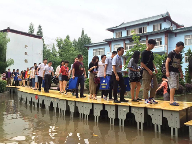 江西省6日发生暴雨，玉山一中校园被水淹没，老师们搬出课桌“搭桥”，让学生可以顺利进入考场应试。