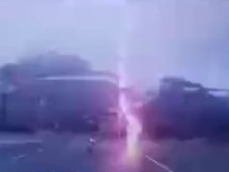一道闪电落下打在骑电单车男子身边约两米的路面上。