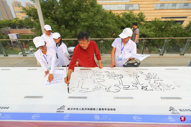 杨拴明在巨幅宣纸上，用一根完整线条勾勒出空心字书法作品。