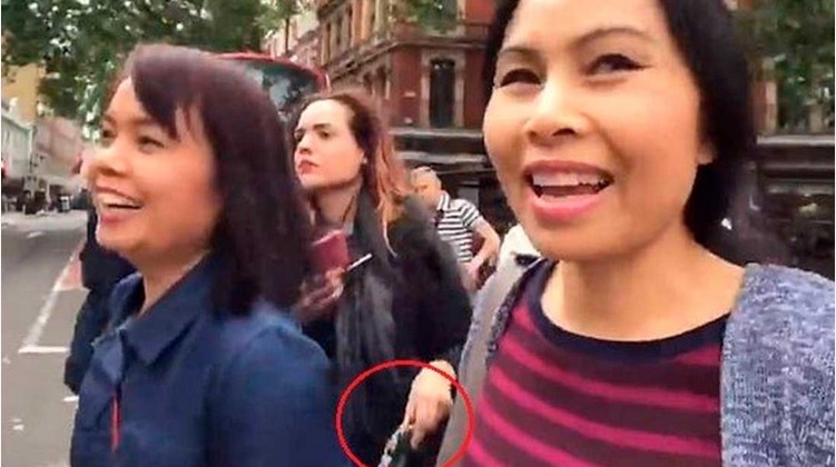 女扒手（中）的一只手（红圈）伸入戴尔（左）的包包。