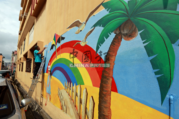 壁画绘图工程在进行中，女孩放风筝的壁画，彩虹背景最夺目。