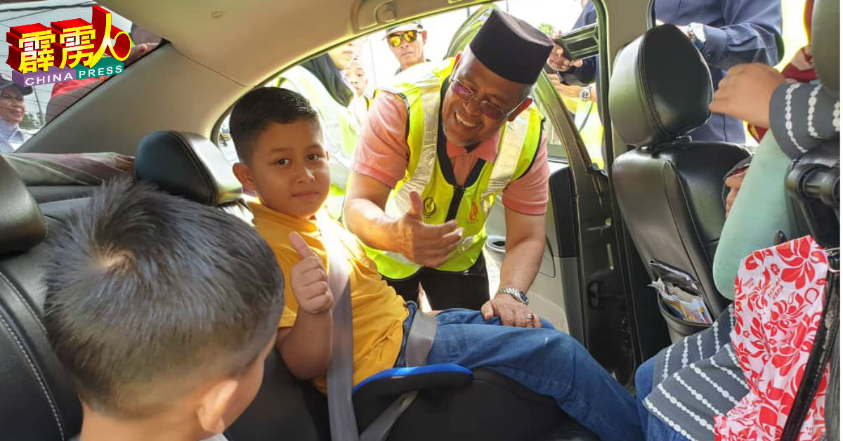 亚哈雅（右）为路过轿车安装儿童安全座椅。