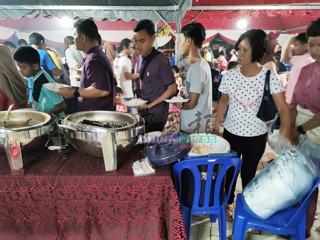 民众拿着现场提供的保丽龙碟子排队拿食物。