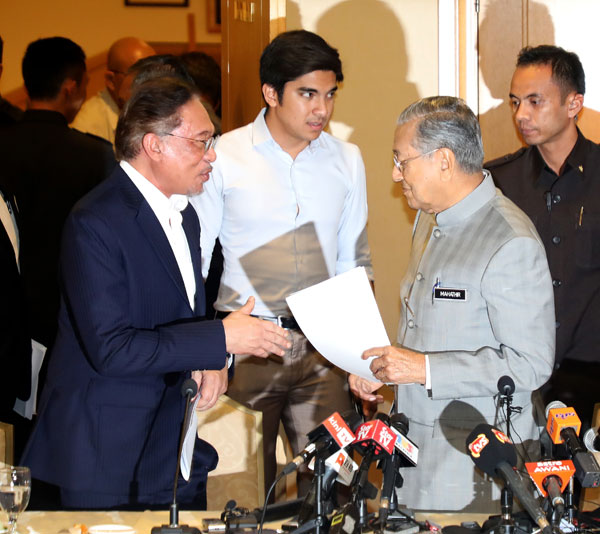 安华（左）在记者会结束后，与马哈迪作简短交谈。