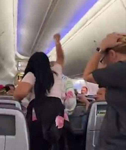 女子在飞机过道上，把手提电脑往男子头上猛砸。