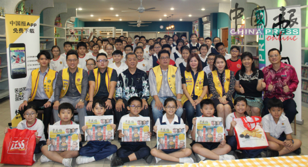同学们手举《中国报》，开心地与嘉宾们合照。