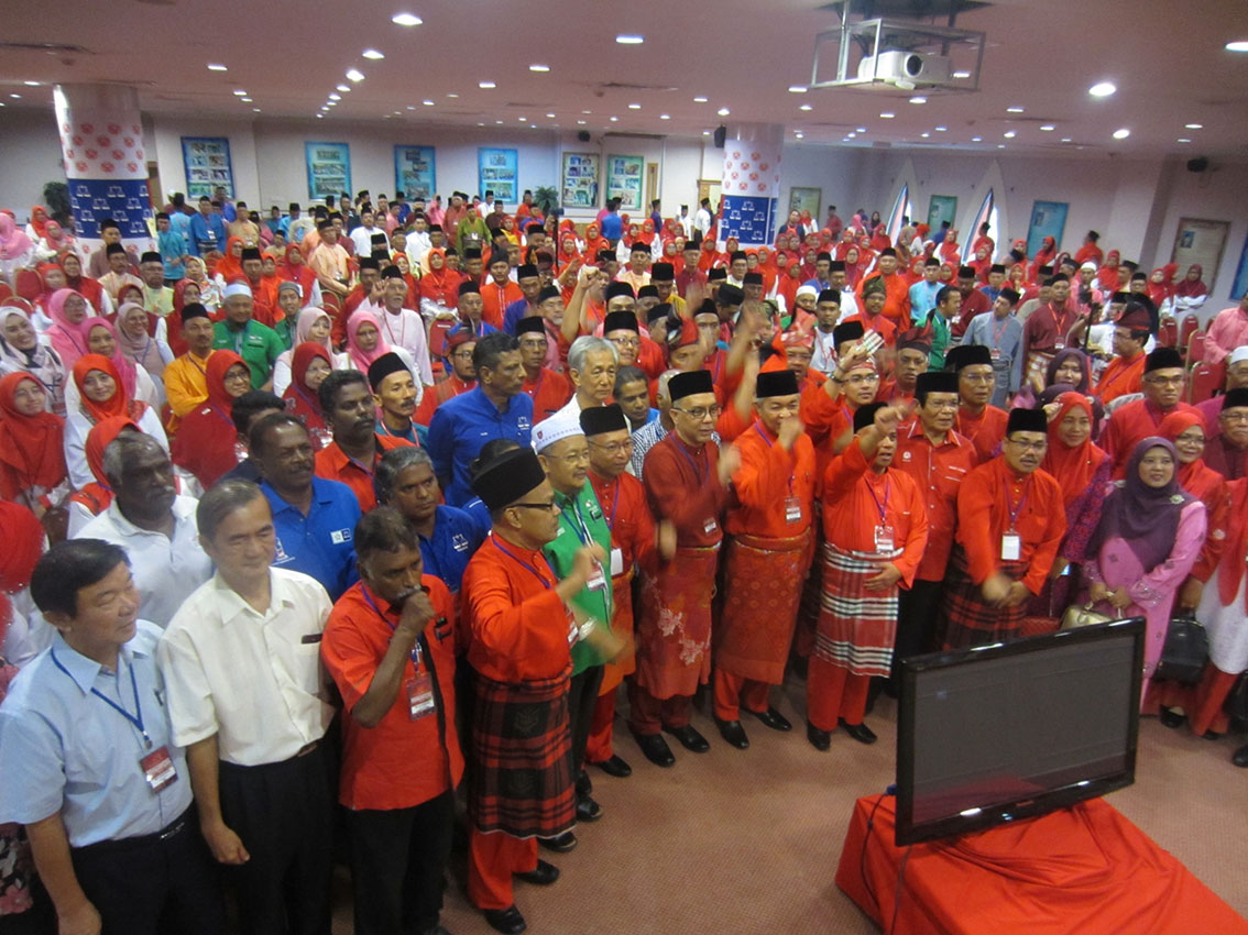 阿末扎希（左8）与出席区部大会的党员，齐举手吁上下重振士气。