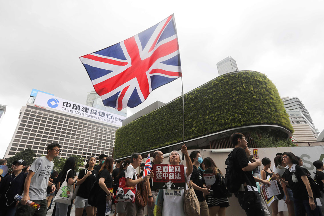 因常在示威场合挥舞英国国旗的“白发婆婆”王凤瑶（中），周日再次带着巨大的英国国旗出场。（法新社）