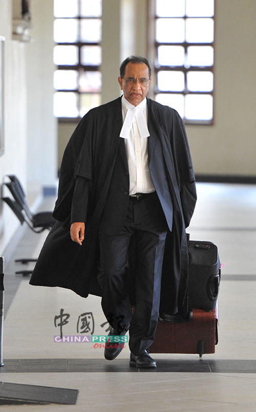 希旦峇兰手拉装有法庭文件的皮箱，步入法庭。