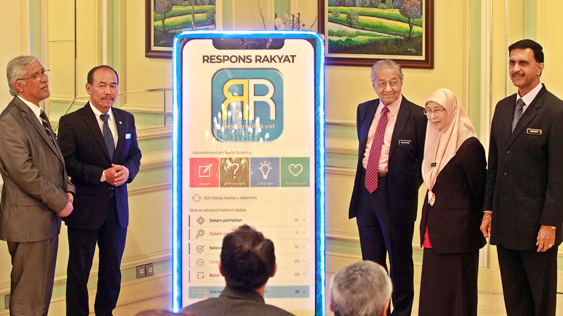 马哈迪（中）推介“人民智能手机反应应用程式2.0”，左起为阿布卡欣、依斯迈和旺阿兹莎。