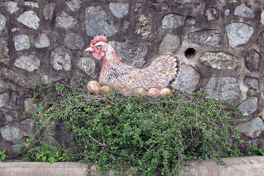 赖昭光以实物配搭，在原本就有的草堆上，画上一只母鸡在窝内下蛋。