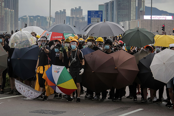  示威者在香港政府总部大楼外举起雨伞，筑起路障。（法新社）
