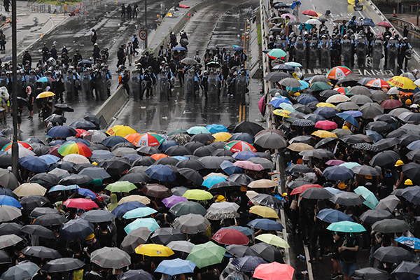持着雨伞的示威者，与镇暴警察狭路相逢。（美联社）