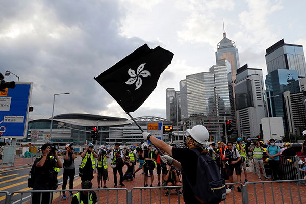 一名示威者挥动着黑色的香港金紫荆旗，企图阻止香港回归庆典的升旗礼。（美联社）