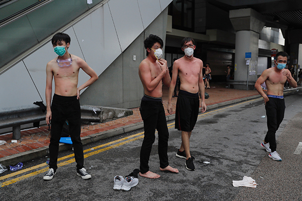 数名示威者被警员喷射胡椒喷雾，他们脱去衣服准备清洗身体。（美联社）