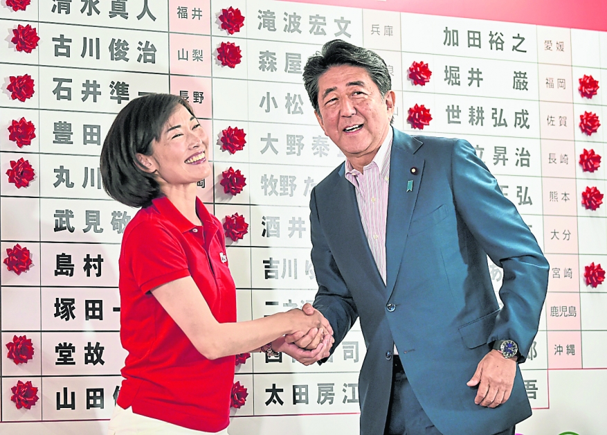 日本首相安倍晋三（右）周日在东京自民党总部，恭贺当选议员丸川珠代。（法新社）