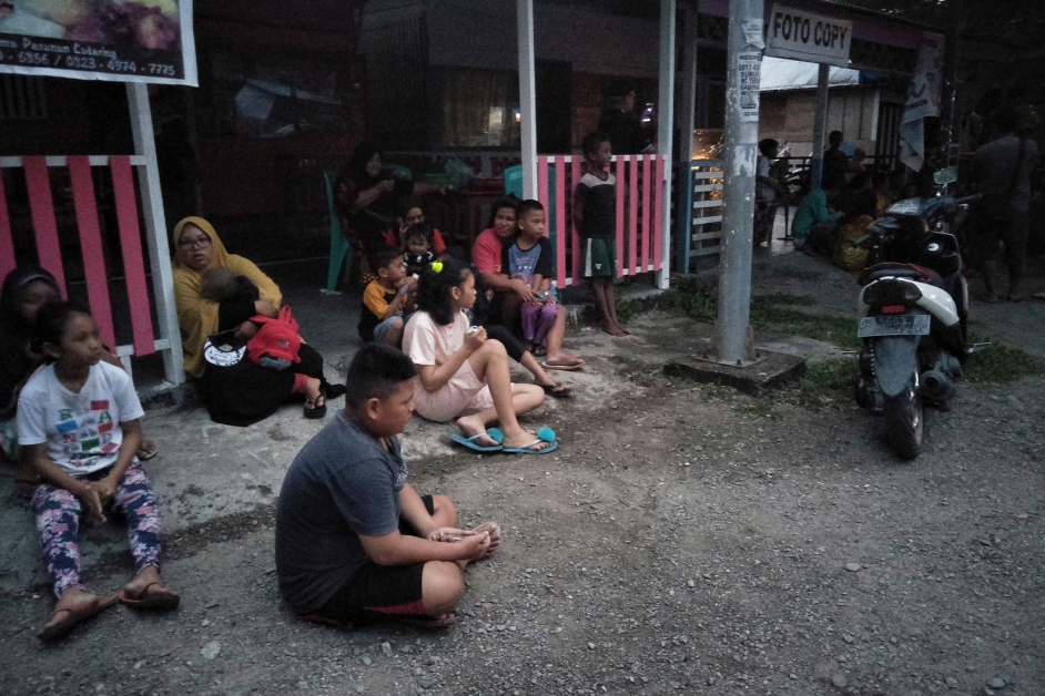 北马鲁古群岛省拉布哈的居民，在地震后跑出屋外避难，他们坐在地上，似乎惊魂未定。（法新社）
