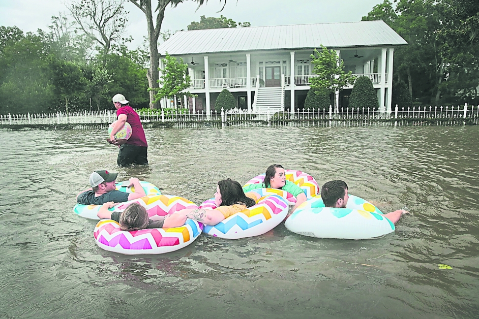飓风“巴里”周六来袭路易斯安那州，该州的曼德维尔区被雨水淹没，居民使用游泳圈“游走”在大路上。