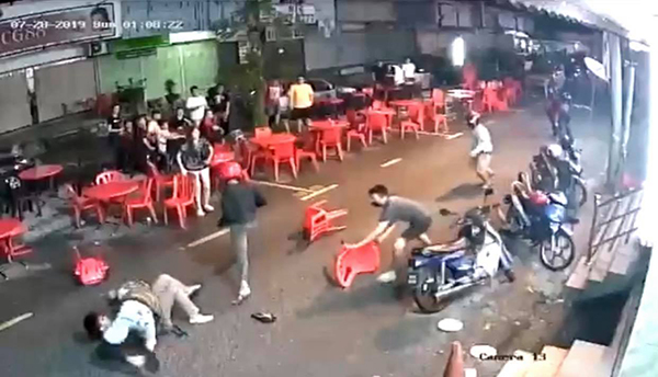 受害者被恶徒压倒在地后，身旁数人即持椅子上前殴打他。