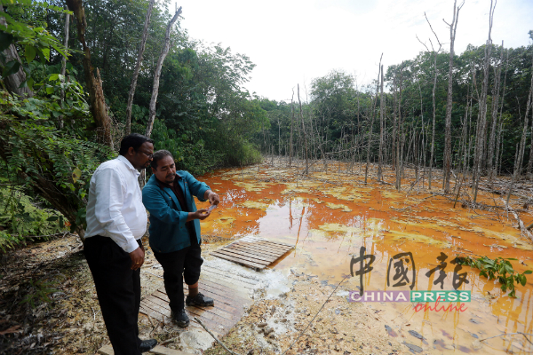环境局官员向威拉班（左）展示废水的酸碱度。