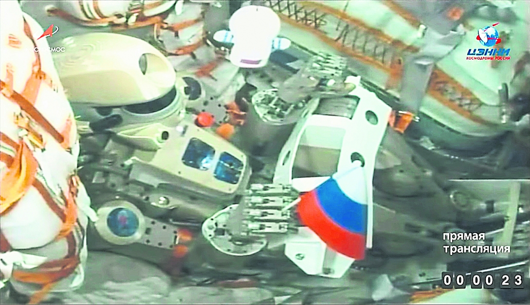 “费多尔”一只手拿着俄罗斯国旗，坐在太空船中飞往国际太空站。（欧新社）