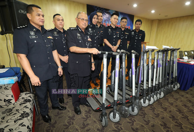 法米（左3）在建功下属陪同下，向记者展示警方起获的15辆电动滑板车。