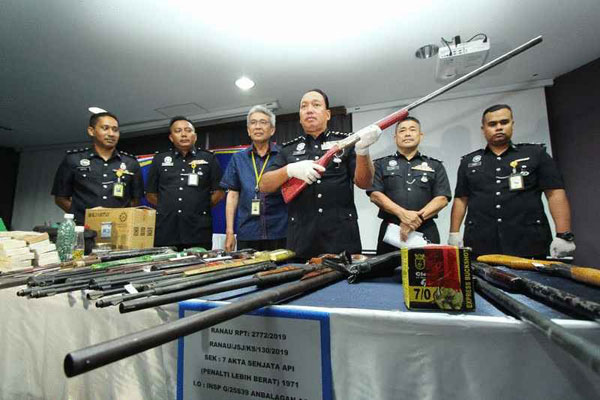 再尼（右三）在警官陪同下，展示兰瑙非法自制土枪案件中起获的土制枪。